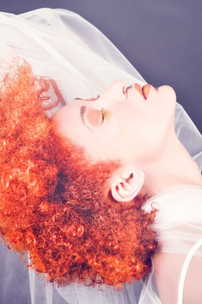 Lady with orange Afro thinks about home hair dye