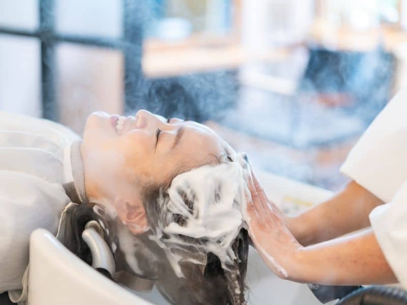 Why Do Salons Wash Your Hair After Coloring? The Science (and Secrets) Behind It 2 why do salons wash your hair after coloring lady being shampooed