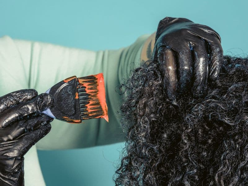 applying hair dye to coily hair roots