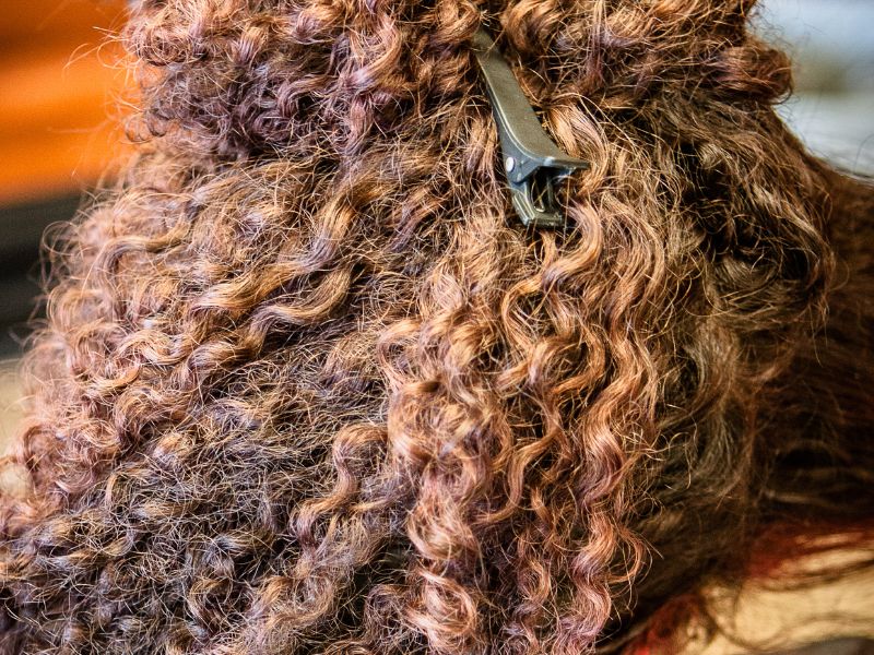 curly. hair being sectioned in a salon for dyeing