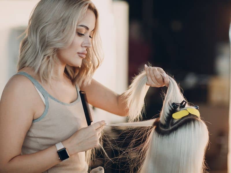 hair stylist in a salon with pearl blonde client