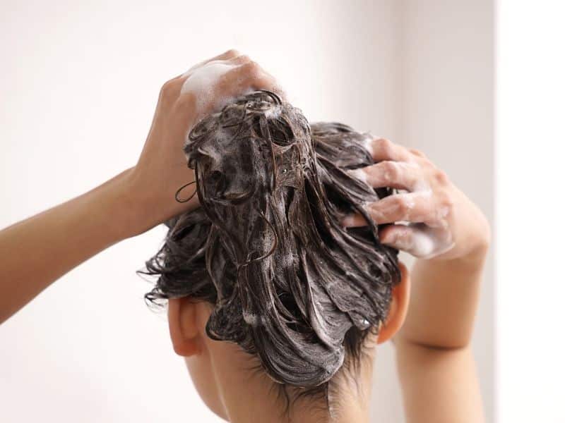 Visualize a person adjusting their washing routine or using lightweight hair products, depicting the lifestyle changes recommended for managing oily hair.