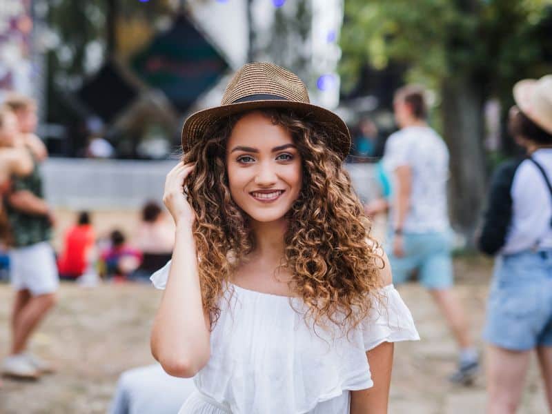 woman wearing a hat at a festival to shield her hair from the sun