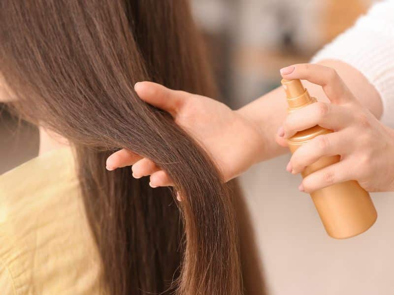 woman using heat protection spray